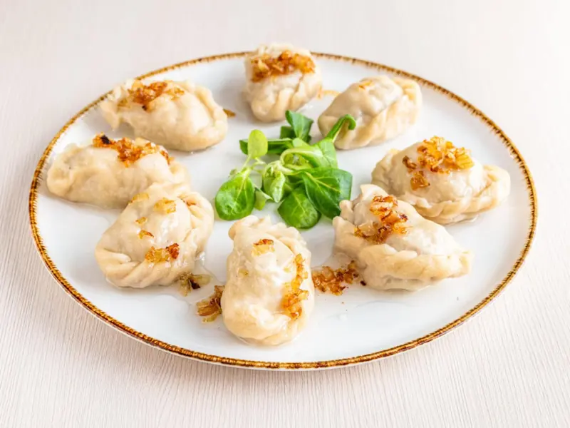 Pierogi z cebulką na talerzu ze złotym brzegiem